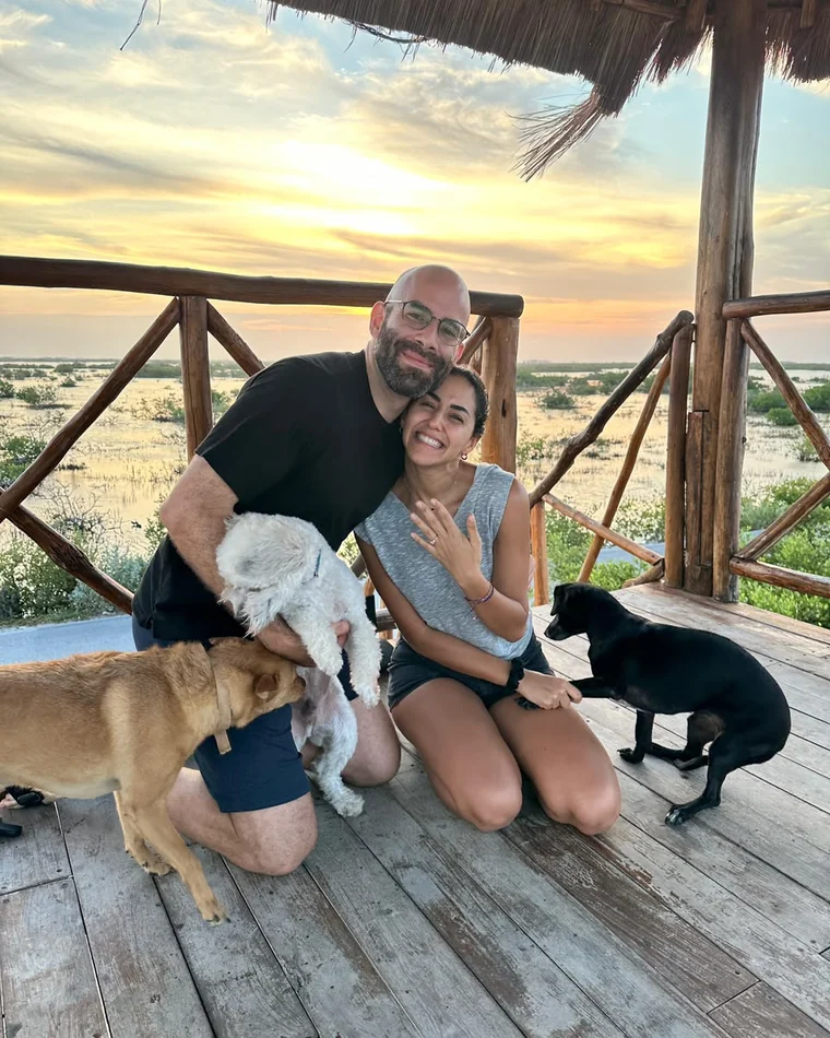 Nora and Marc kneeling together at sunset, surrounded by their dogs